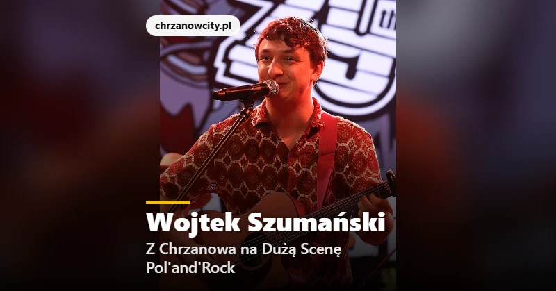 Wojtek Szumański śpiewa z gitarą przy mikrofonie na scenie festiwalu
